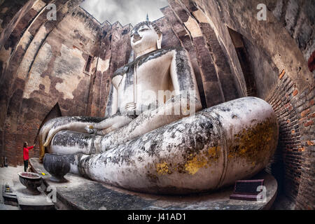 Frau im roten t-Shirt stehen in der Nähe von riesigen Buddha-Statue Phra Achana in Wat Si Chum in Sukhothai Historical Park, Thailand anrufen Stockfoto