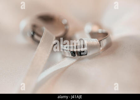 Trauringe auf einem weißen satin Kissen. Zubehör Hochzeit Closeup. selektiven Fokus Stockfoto