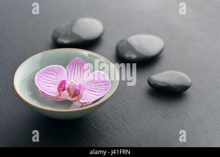 Spa-Steinen und rosa Orchidee auf schwarzem Schiefer Hintergrund Stockfoto