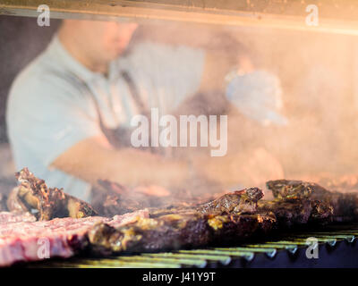 Grillen rotes Fleisch und Wurstwaren bei Sonnenuntergang im Freien mit Freunden und Familie zu sammeln, Stockfoto