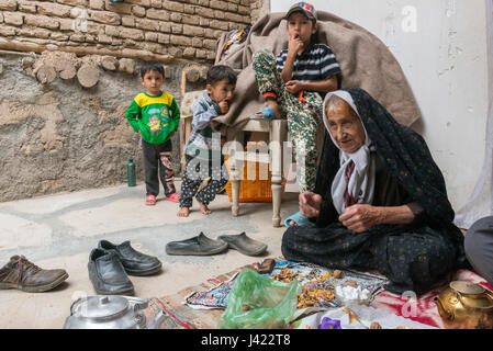 Alte Dame und Enkel in ihrem Haus bietet hausgemachte Köstlichkeiten, Besucher, Esfidan, ein traditionelles Dorf, Nord-Chorasan, IRAN Stockfoto