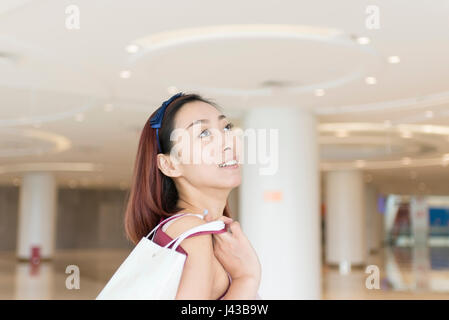 Nachdenkliche Frau Holding Einkaufstaschen in der mall Stockfoto