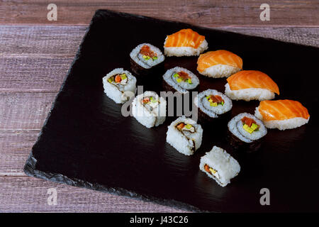 Große Anzahl von japanischen rollt auf einem schwarzen Steinplatte rollt Sushi japanischen Küche Stockfoto