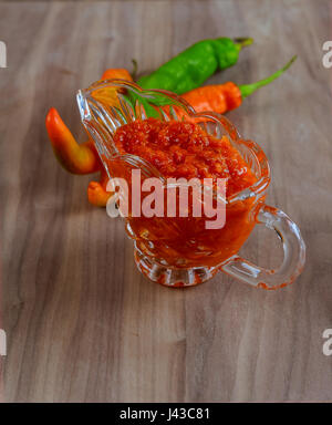 Tabasco Adjika in ein Glas Sauciere, Peperoni, Knoblauch, Petersilie, Bockshornklee, Öl in die Karaffe auf dem Hintergrund der Sack Tuch Stockfoto