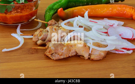 Traditionelle leckeres Schaschlik Spieß Grill Putenfleisch mit Tomaten, Paprika und Sauce auf Keramikschale. Serviert auf Holztisch Hintergrund. Rost Stockfoto