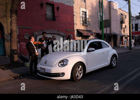 Mariachi-Musiker spielen traditionelle Lieder für ein Paar, das in einem Auto auf der Straße in der mexikanischen Hauptstadt sitzt Stockfoto