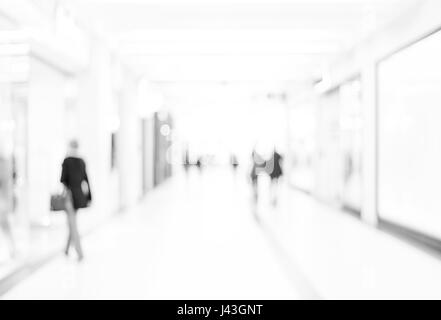 Verschwimmen Sie Shop mit Bokeh Hintergrund. Silhouetten von Geschäftsleuten in Bewegungsunschärfe zu Fuß. Geschäftsleute im Büro Flur gehen. Stockfoto