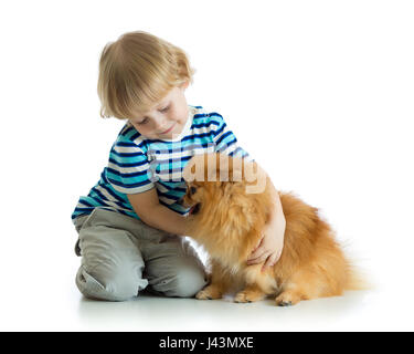 Kid Boy umarmt Hund Spitz isoliert auf weißem Hintergrund Stockfoto