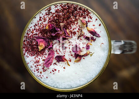 Rosenblättern garniert Latte Schaum Stockfoto