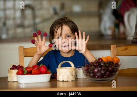 Süß süßes Kind, junge, Essen, frisches Obst zu Hause, Erdbeeren, Kirschen, Himbeeren, Heidelbeeren Stockfoto