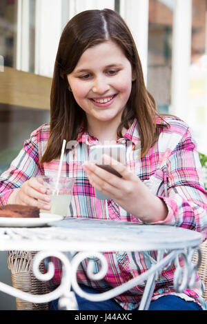 Junges Mädchen im Cafe lesen SMS auf Handy Stockfoto