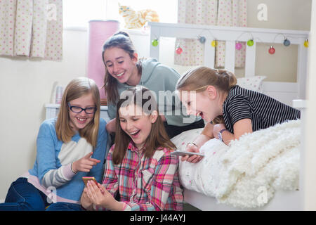 Gruppe junger Mädchen mit Mobiltelefonen im Schlafzimmer Stockfoto