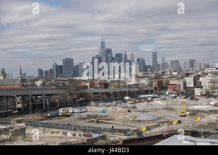 Die industrielle Gowanus Brooklyn Nachbarschaft im Vordergrund mit dem F-Zug oben Boden Spalier mittlere und die untere Manhattan Skyline hinter sich abzeichnenden. Blick von der Smith / 9th Street u-Bahnstation erhöht. Stockfoto