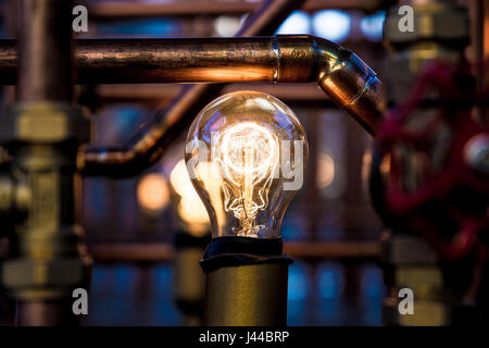 Weißglühende Glühlampe zwischen rostigen Rohren Stockfoto