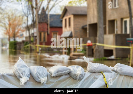 Schließen Sie Schuss von Hochwasser Schutz Sandsäcke mit überfluteten Häusern im Hintergrund Stockfoto