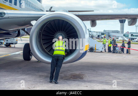 Überprüfung des Motors von Ryanair Boeing 737 am Manchester Flughafen während Passagiere Warteschlange Flugpersonal Stockfoto