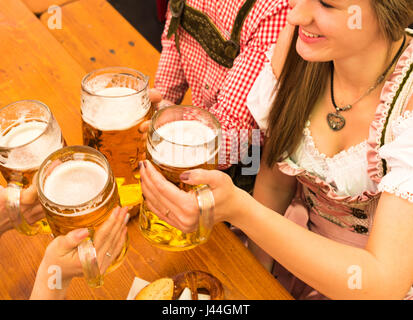 Junges Paar Toasten im Oktoberfest-Bierzelt Stockfoto