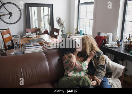 Ein junges Paar küssen auf dem sofa Stockfoto