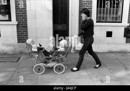 Twin Pram 1980s UK. Junge Mutter Mutter Mutter Frau schiebt junge Zwillinge in einem Doppelwagen Buggy Kinderwagen Battersea London England 1983 HOMER SYKES Stockfoto