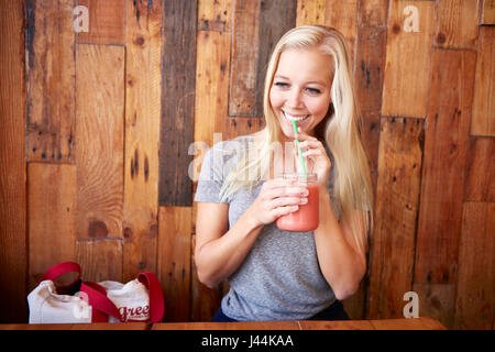 Glückliche gesunde junge Frau trinken frisch gepresst Saft in einem café Stockfoto