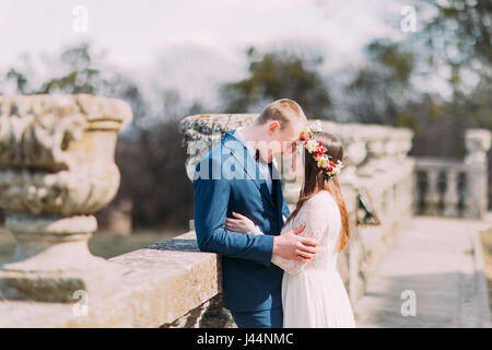 Porträt von stilvollen Brautpaar posiert auf alte Steinterrasse im Frühlingspark und liebevoll durch die Stirn berühren Hochzeit Stockfoto