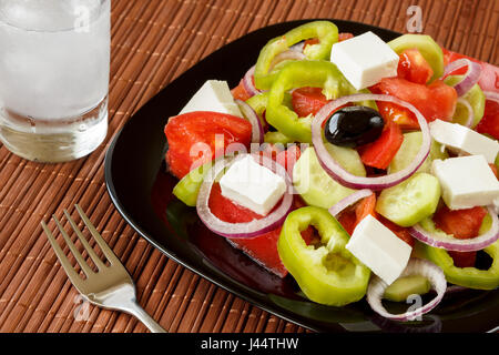 Glas Ouzo trinken und frischer Salat mit grünem Pfeffer und roten Zwiebelringen, Tomaten, Gurken und Hüttenkäse. Traditionelle balkan Küche Vorspeise Stockfoto