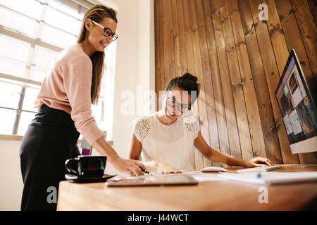 Lächelnde kreative Business-Frauen am Schreibtisch. Zwei weibliche Kollegen zusammenarbeiten. Stockfoto