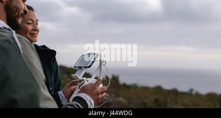 Junges Paar eine Drohne mit Fernbedienung navigieren. Mann und Frau in Landschaft fliegenden Drohne. Stockfoto