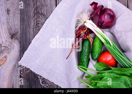 Frisches Gemüse aus Gemüse Garten Tomaten, Zwiebel, Gurke auf grau Serviette, hölzerne grauen Hintergrund, leeren Raum auf der linken Seite Stockfoto