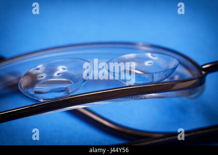 Zwei transparente weicher Kontaktlinsen liegen auf der Linse der normalen Brille Stockfoto