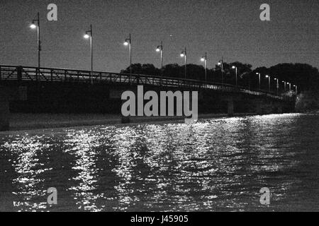 Körnige schwarz-weiß Foto der Lichter beleuchten die Spottdrossel Fußgängerbrücke in der Nacht am nördlichen Ende des White Rock Lake in Dallas, Texas Stockfoto