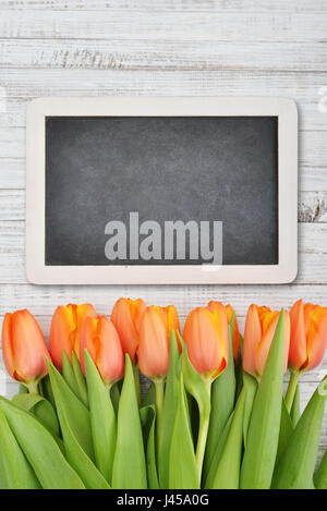 Rote Tulpen mit Tafel über schäbigen weißen hölzernen Hintergrund, Ansicht von oben Stockfoto