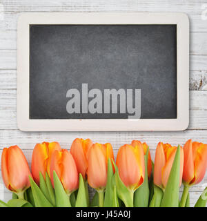 Rote Tulpen mit Tafel über schäbigen weißen hölzernen Hintergrund, Ansicht von oben Stockfoto