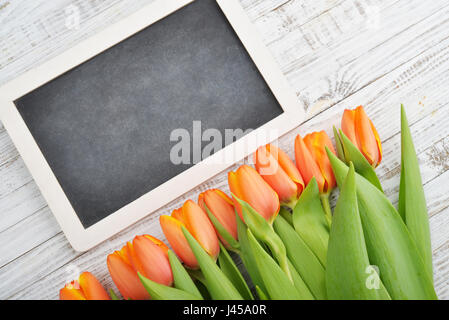 Rote Tulpen mit Tafel über schäbigen weißen hölzernen Hintergrund, Ansicht von oben Stockfoto