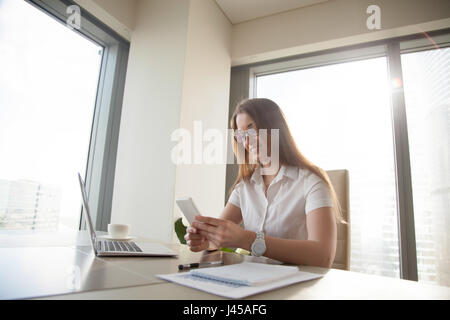 Faule Frau spielen am Telefon am Arbeitsplatz Stockfoto