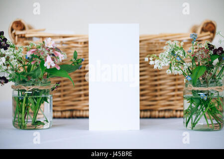 Hochzeit Kartenvorlage auf Korb Hintergrund neben Blumen in Gläsern Stockfoto