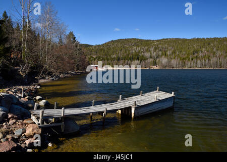Holzsteg an der Ostsee-Küste mit Berg und einem blauen Himmel im Hintergrund, Bild aus Nordschweden. Stockfoto