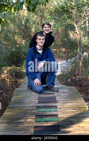 Schwester und Bruder Pause in Ihrer schlendern Sie durch den Süden von Arkansas Arboretum in El Dorado, Arkansas. Bruder kniet auf Holzsteg und Schwester l Stockfoto