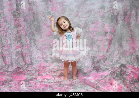 Baby Ballerina zeigt ihre Ballett-Moves.  Sie ist in einem rosa, blauen und weißen Tutu bekleidet.  Sie hat ihren Arm angehoben und die andere an ihrer Hüfte. Stockfoto