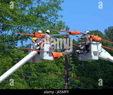 Drei Eimer LKW heben Linemen zum Seitenanfang Strom Pol. Drei Mechaniker Wissen kombinieren und Stromausfall zu reparieren. Stockfoto