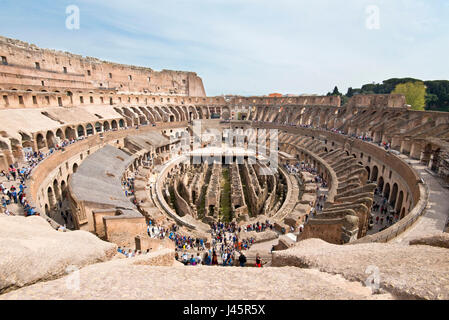 Ein Weitwinkel Innenansicht des Amphitheaters im Inneren des Kolosseums mit Touristen Besucher an einem sonnigen Tag mit blauem Himmel genommen von der obersten Ebene 3. Stockfoto