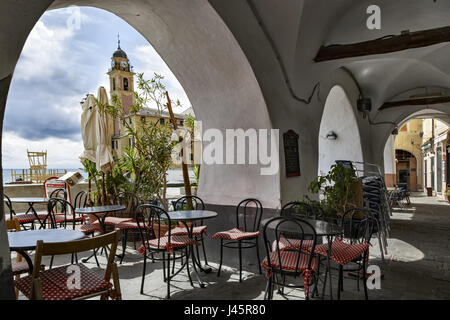 Von einem verdeckten Restaurant mit offenen Bögen mit Blick auf die Uferpromenade Kirche in Camogli, ein beliebter Urlaubsort an der italienischen Riviera anzeigen Stockfoto