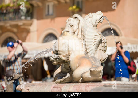 Eine Nahaufnahme auf die Fontana del Moro oder Moor-Brunnen auf der Piazza Navona mit 2 out of Focus Menschen Touristen Besucher im Hintergrund zu fotografieren. Stockfoto