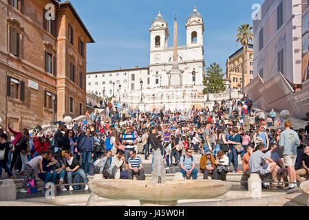 Spanische Treppe in Rom mit Touristen an einem sonnigen Tag mit blauem Himmel Trinità dei Monti Kirche im Hintergrund und Brunnen des hässlichen Boot Vordergrunds. Stockfoto