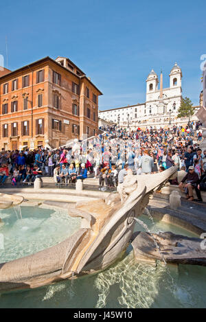 Spanische Treppe in Rom mit Touristen an einem sonnigen Tag mit blauem Himmel Trinità dei Monti Kirche im Hintergrund und Brunnen des hässlichen Boot Vordergrunds. Stockfoto