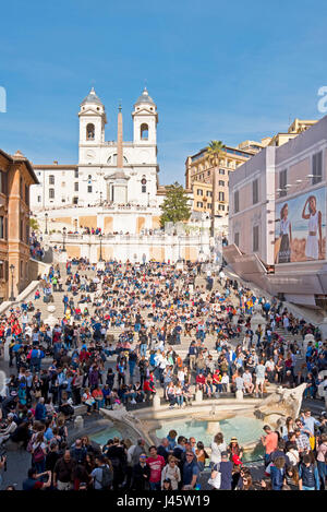 Spanische Treppe in Rom mit Massen von Touristen an einem sonnigen Tag mit blauem Himmel Trinità dei Monti Kirche Hintergrund Brunnen des hässlichen Boot Vordergrunds. Stockfoto