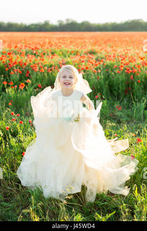 aufgeregt, Wochenenden, Feier, Sommer, Kind, Kind Modekonzept - wenig freudige blonde Mädchen in weißen Sonntagskleid mit Tüll-Rock-Lughing und springen mitten im Mohnfeld Stockfoto