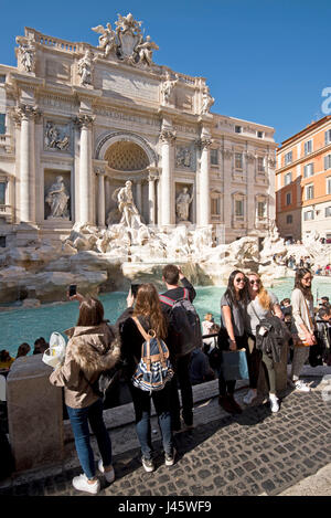 Der Trevi-Brunnen "Fontana di Trevi" in Rom mit Massen von Touristen und Besucher nehmen Fotos, posieren und Selfies an einem sonnigen Tag mit blauem Himmel. Stockfoto