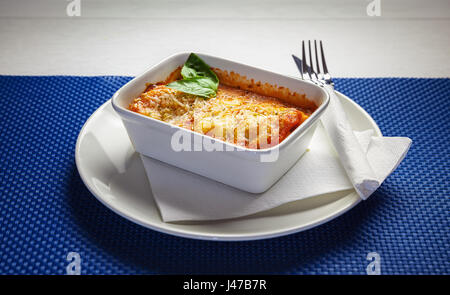 Lasagne in weißer Teller mit grünen Blatt verziert. Stockfoto