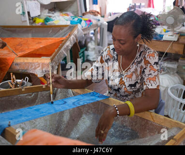 Eine Frau malt eine Batik-Design auf Stoff in der Art Fabrik Arbeitszimmer in St. George's, Grenada, West Indies, Karibik Stockfoto